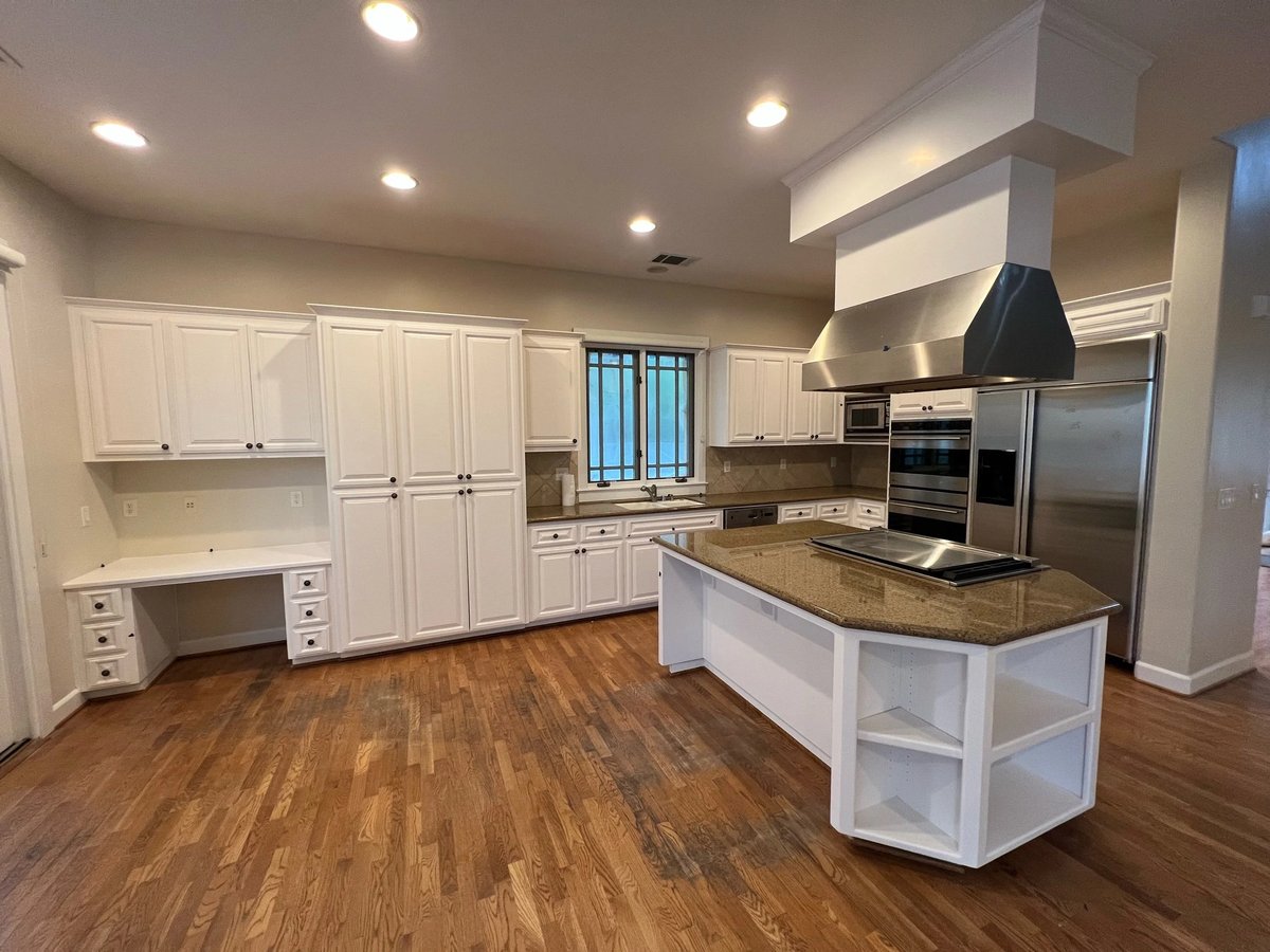 Bright kitchen with white cabinetry and hood surround